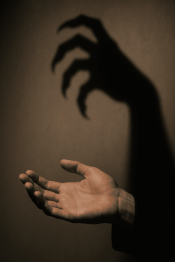 Hand offering help with a shadow that looks predatory, symbolizing manipulation disguised as kindness.